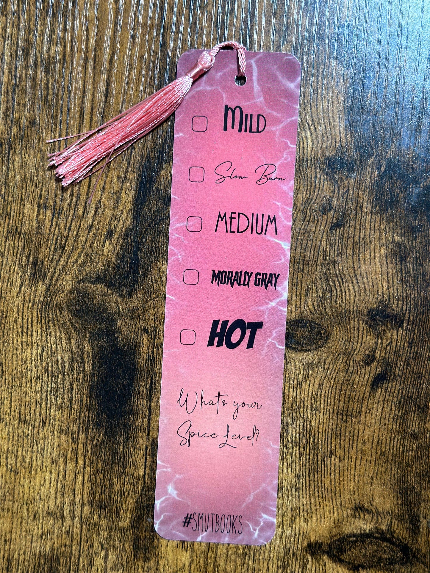 Pink bookmark with text and checkboxes on a wooden surface