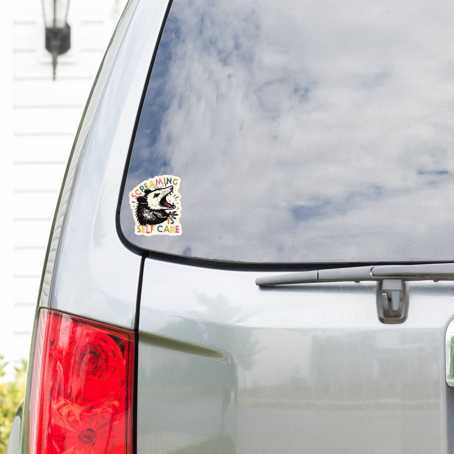 Car with a sticker on the rear window, reflecting clouds.