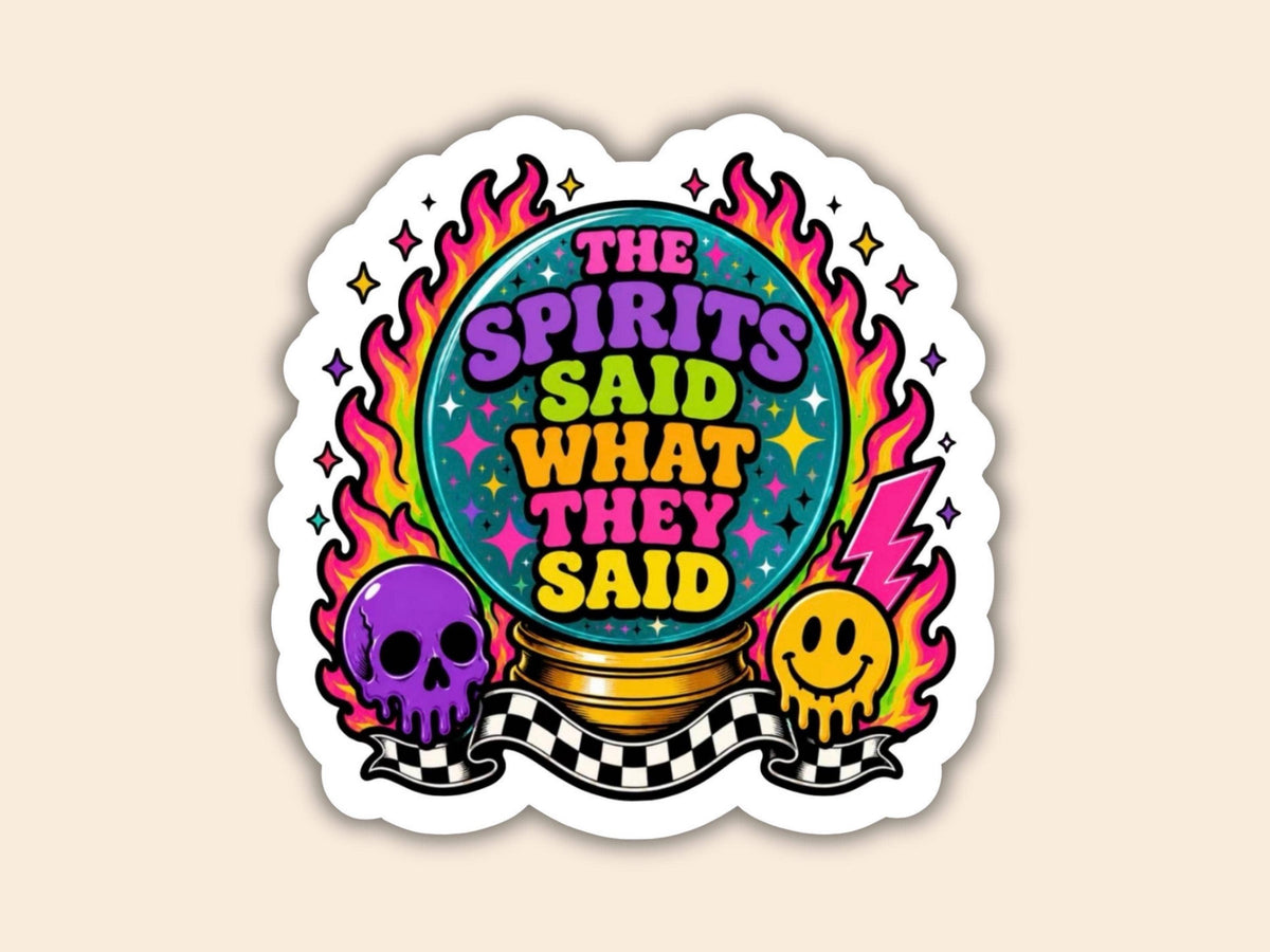 A die-cut sticker featuring the text 'THE SPIRITS SAID WHAT THEY SAID' in colorful retro lettering inside a crystal ball, surrounded by pink and orange flames, a purple skull, a yellow smiley face, and a black-and-white checkered banner, shown on a light beige background.