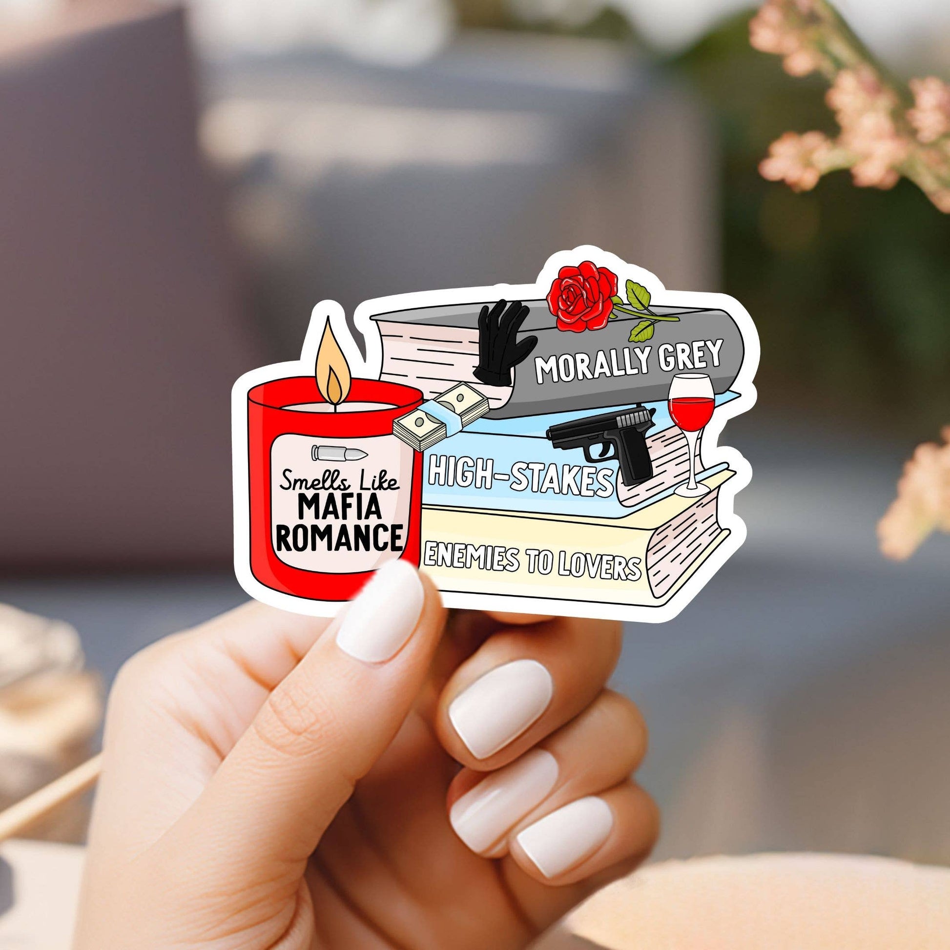 Hand holding a sticker with book-themed design and text.