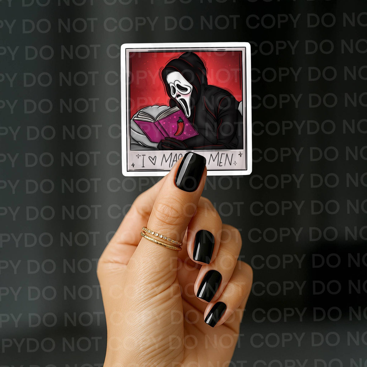A hand with black nail polish holds a square sticker featuring a horror character in a black mask reading a pink book against a red background, with the text 'I ♥ MADE MEN.' at the bottom.