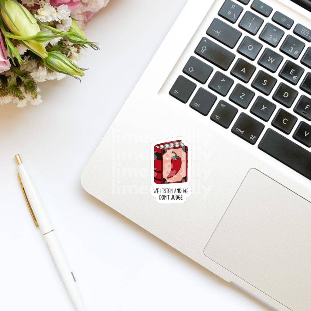 Laptop with a sticker on a white surface with flowers and a pen.