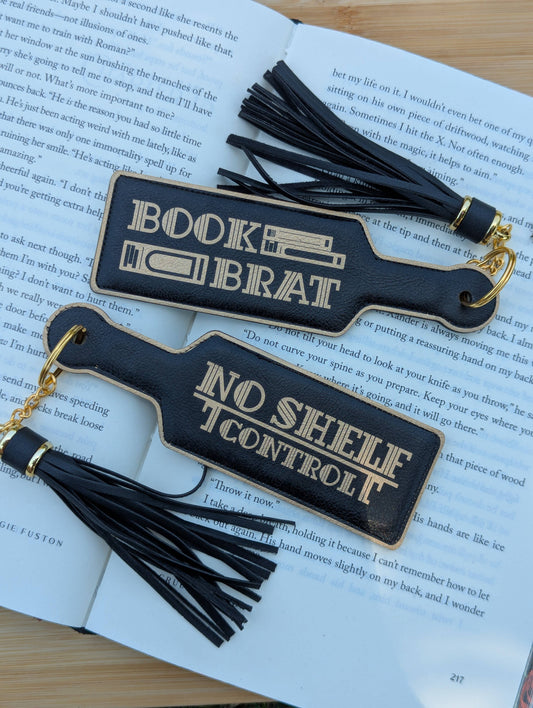 Two black bookmarks with tassels on an open book