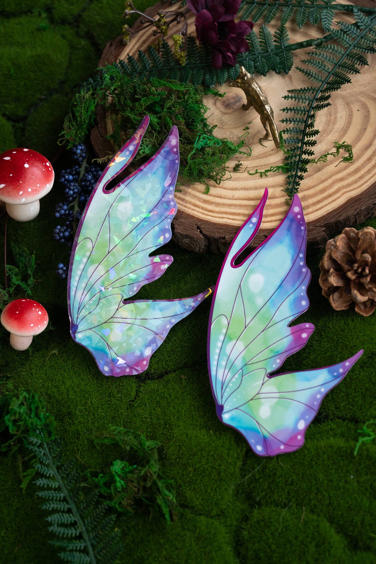 Colorful fairy wings on a natural background with greenery and mushrooms.