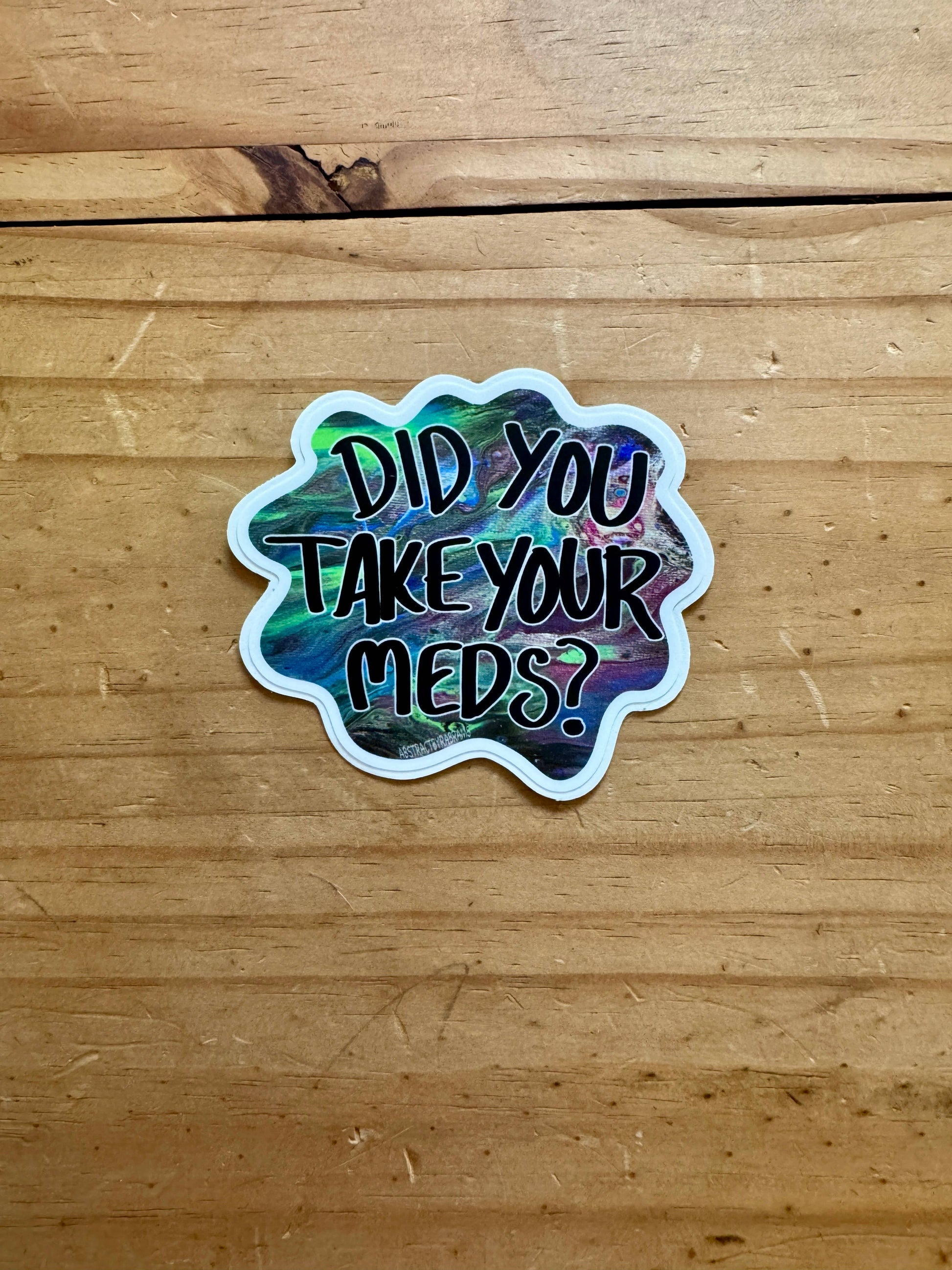 Sticker with 'Did you take your meds?' text on a wooden surface