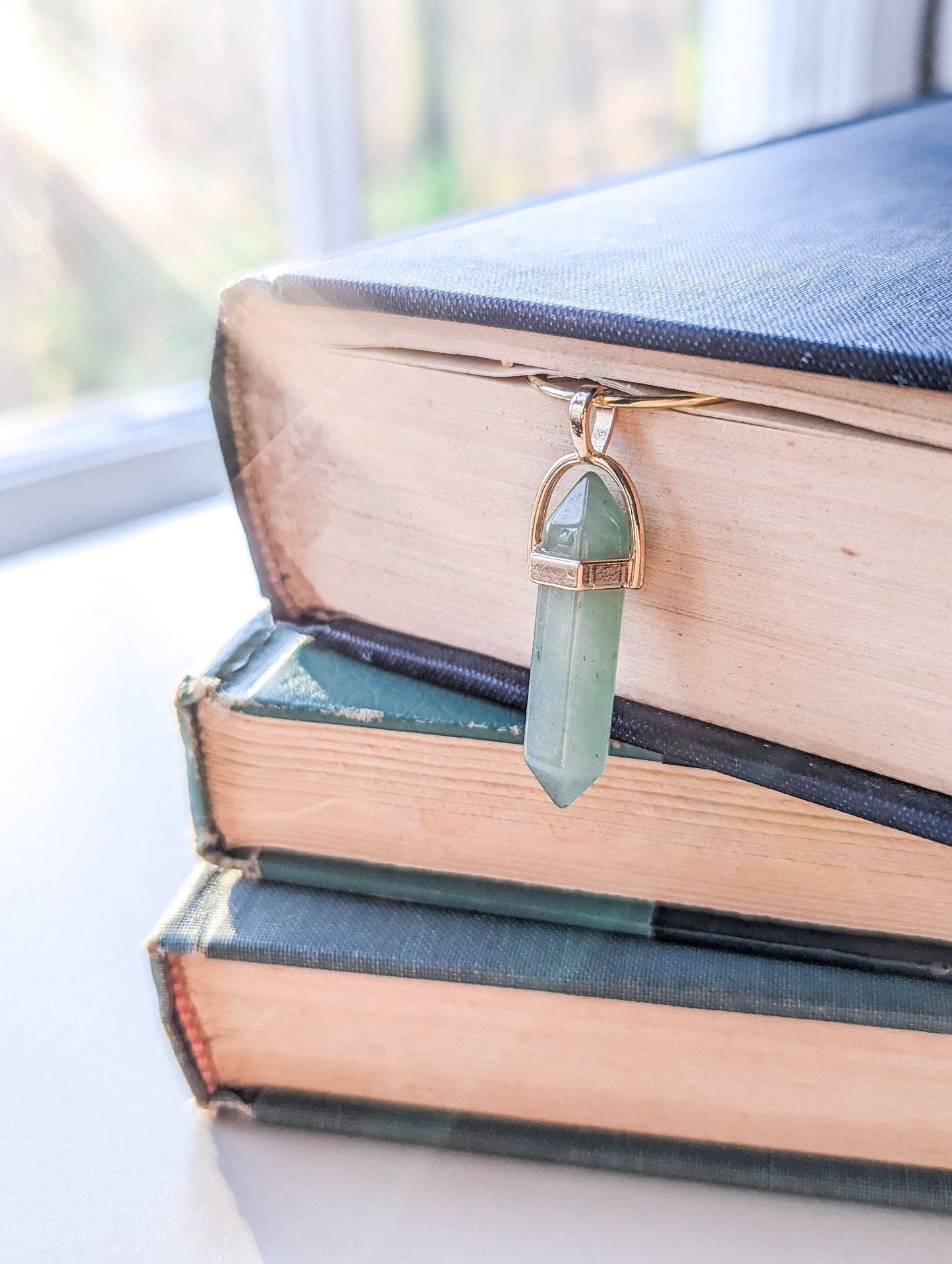 Green crystal pendant on a stack of books with a blurred background