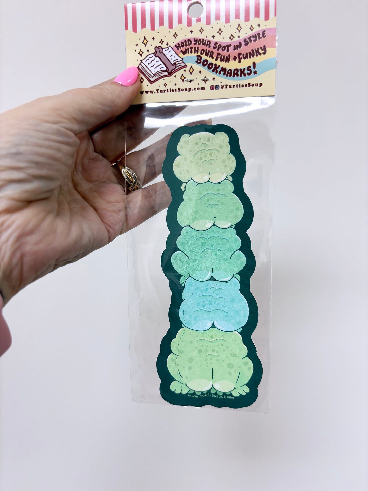 Hand holding a set of green and blue gradient bookmarks with packaging labeled 'Turtleshop'.