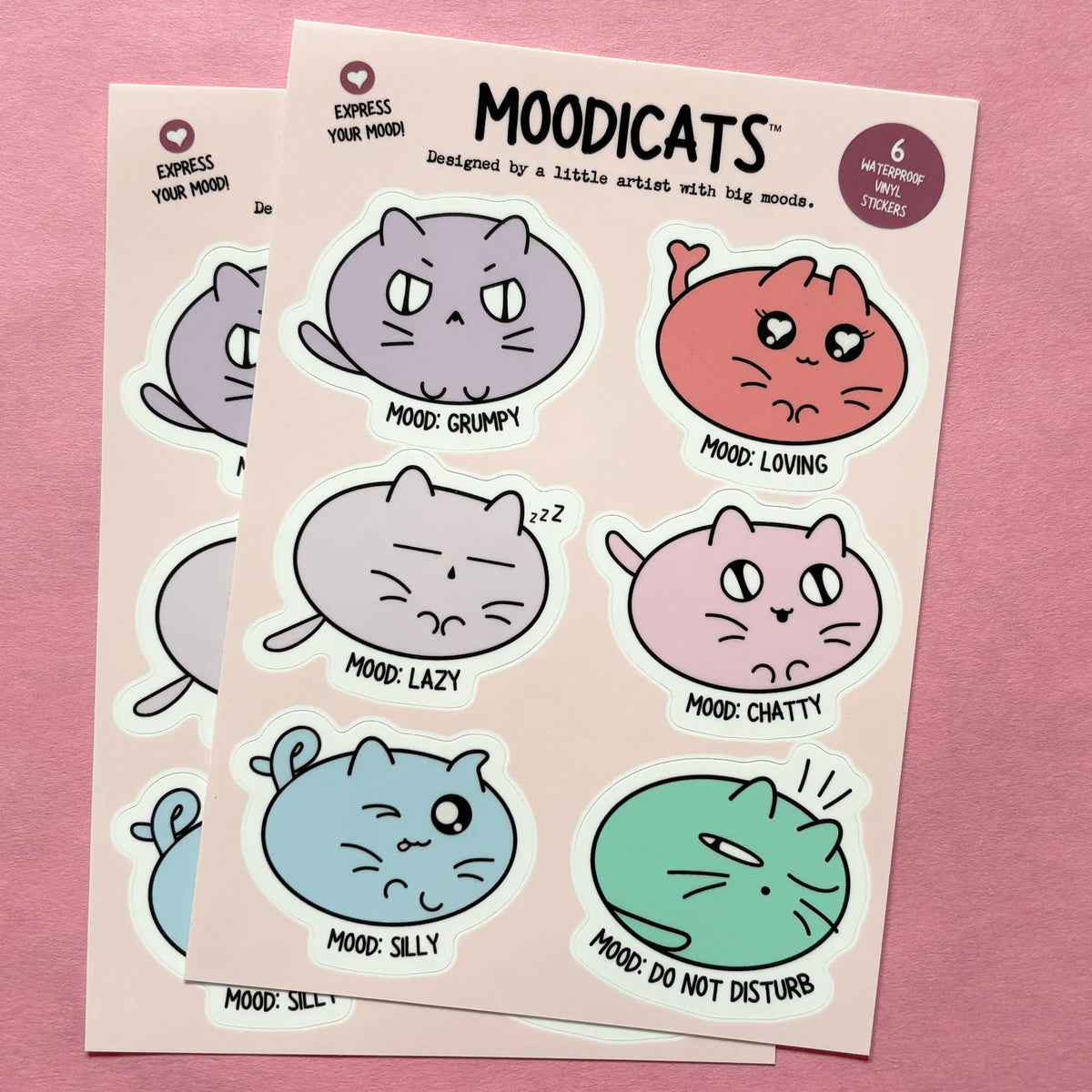 Two sticker sheets featuring cute cartoon cats in different moods, displayed on a pink background. The stickers are in pastel shades of purple, coral, gray, pink, blue, and green, with text labels like 'MOOD: GRUMPY', 'MOOD: LOVING', 'MOOD: LAZY', 'MOOD: CHATTY', 'MOOD: SILLY', and 'MOOD: DO NOT DISTURB'.