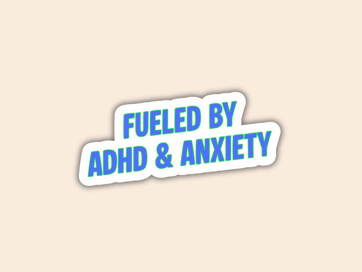 A die-cut sticker with the text 'FUELED BY ADHD & ANXIETY' in blue letters on a white background with a gray shadow, set against a solid beige backdrop.