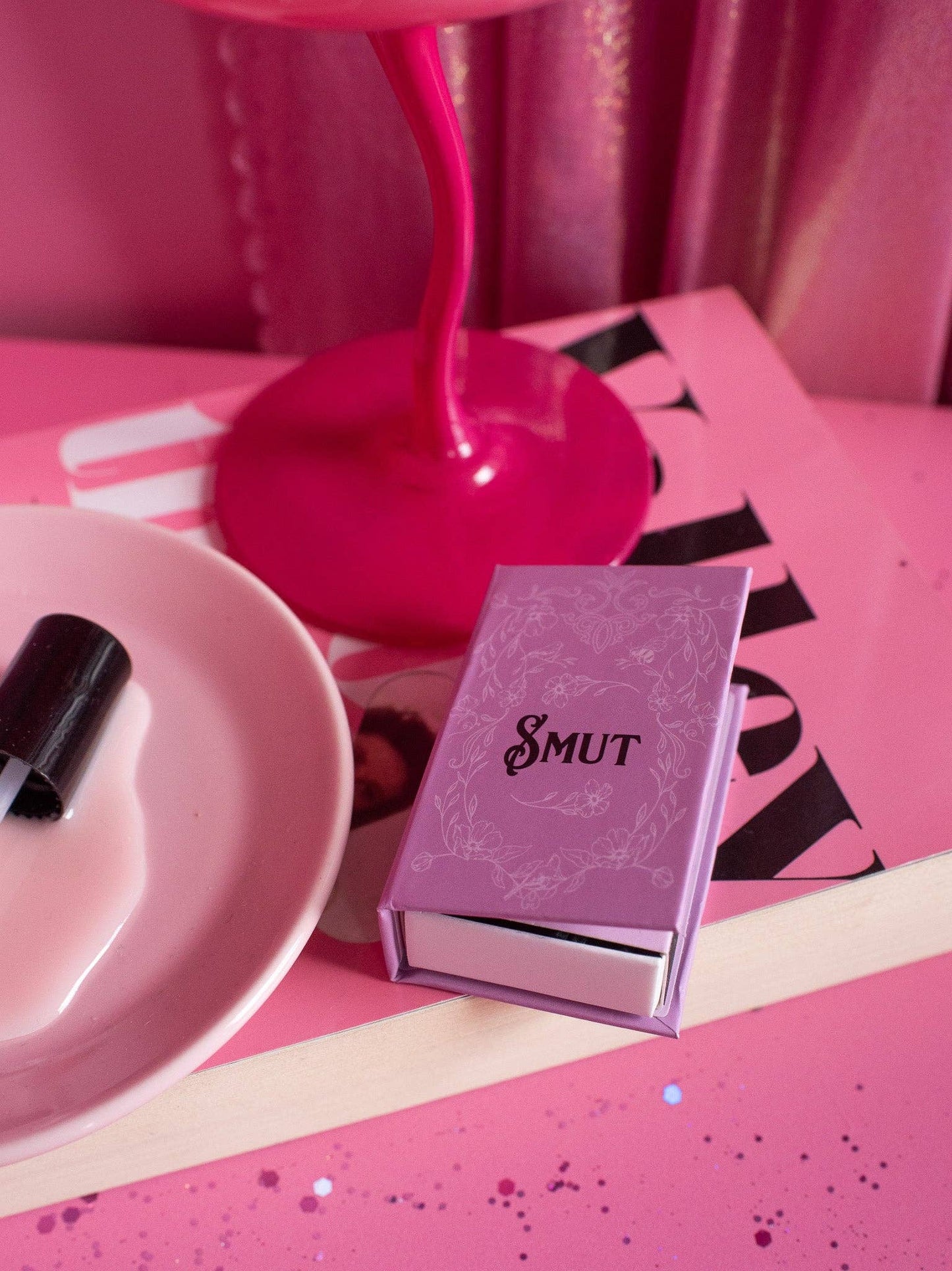 Pink book titled 'Smut' on a pink surface with a pink lamp in the background.