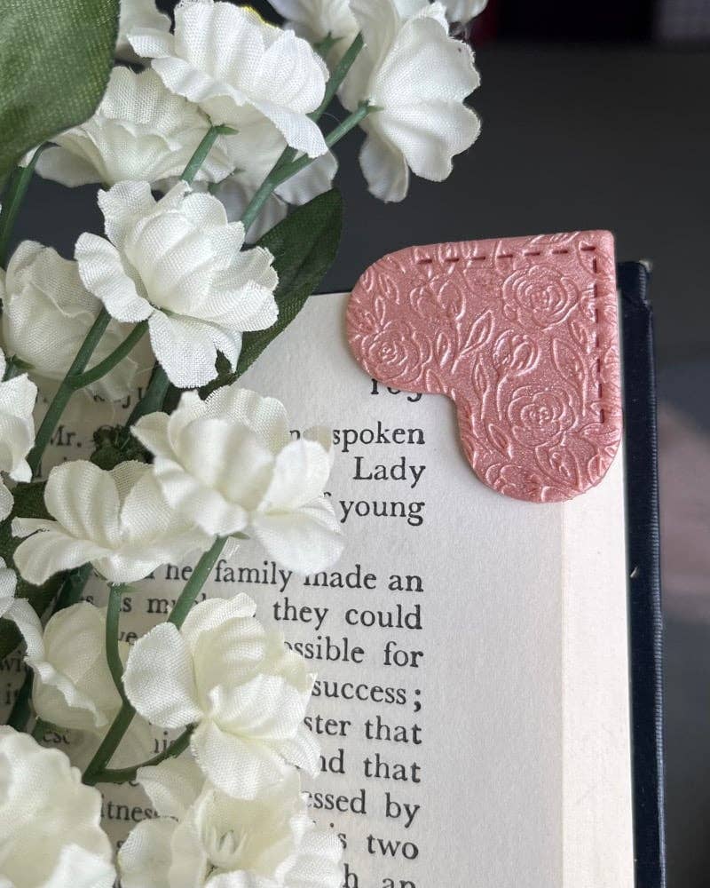 Heart-shaped pink clay bookmark on a book with white flowers