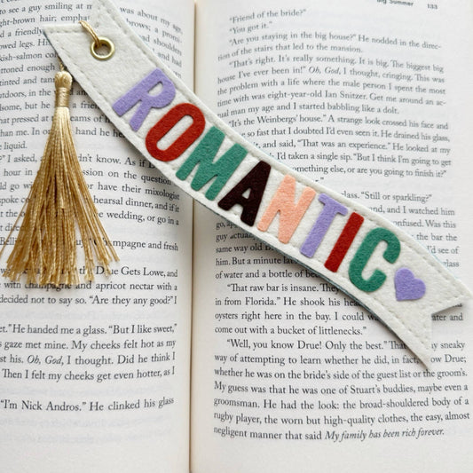 Colorful 'ROMANTIC' bookmark with tassel on an open book