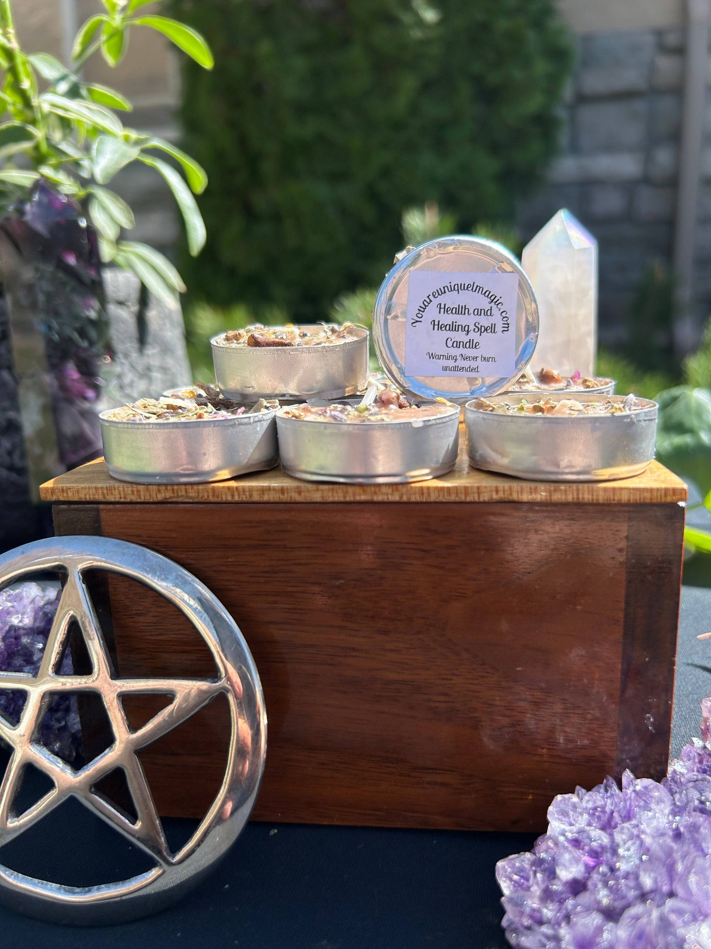 Candles in metal tins on a wooden stand with a pentacle symbol in the foreground.