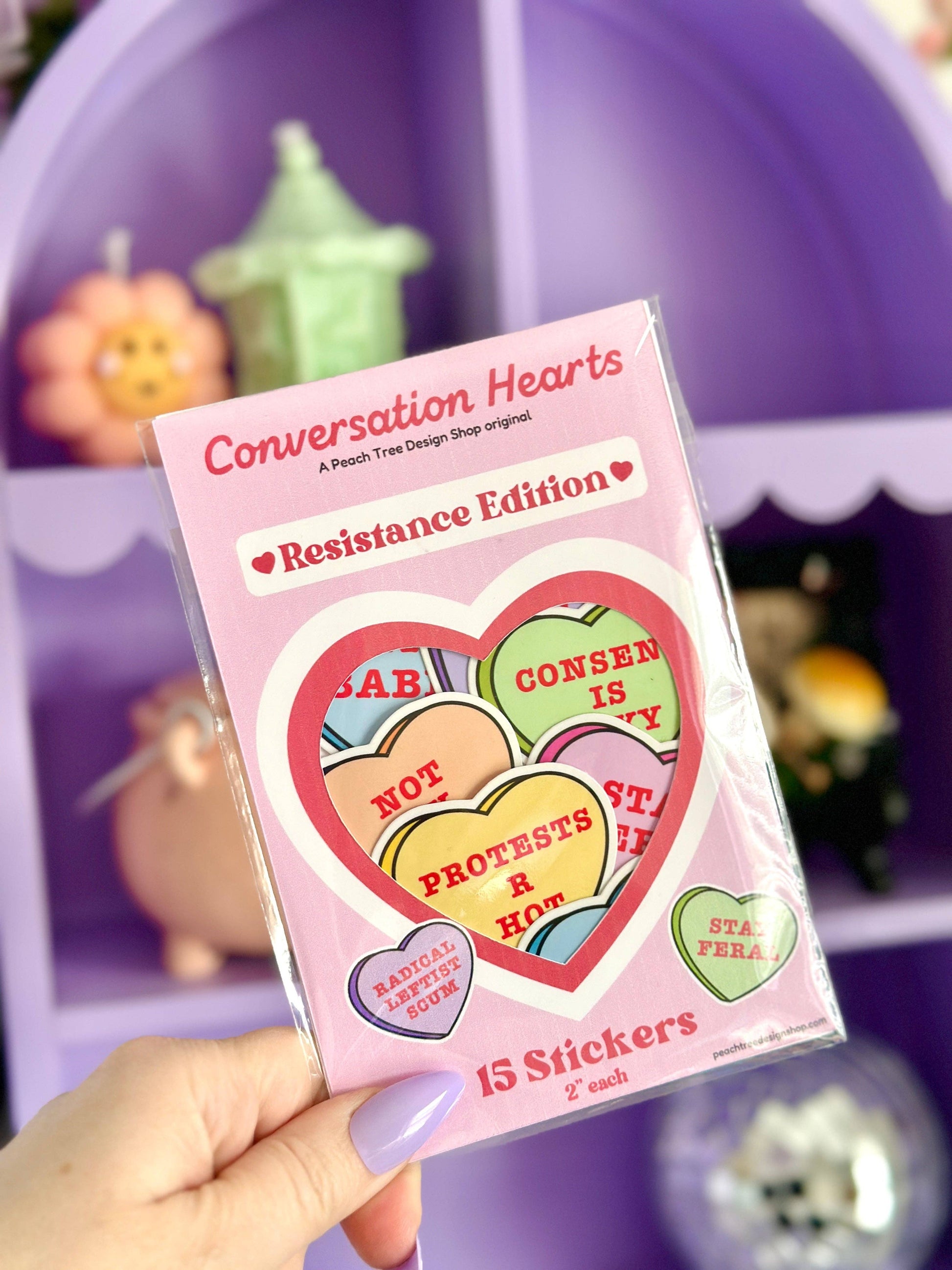 Pack of 'Conversation Hearts' stickers held by a hand with a colorful background