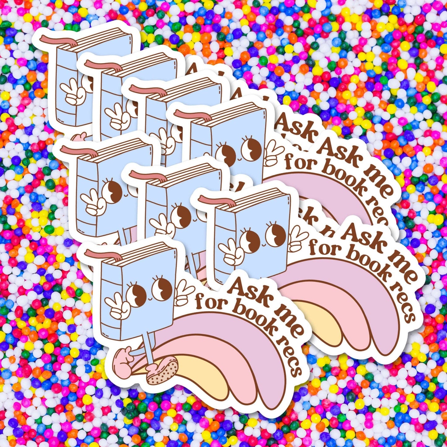 Cartoon books with faces and text 'Ask me for book recs' on a multicolored background