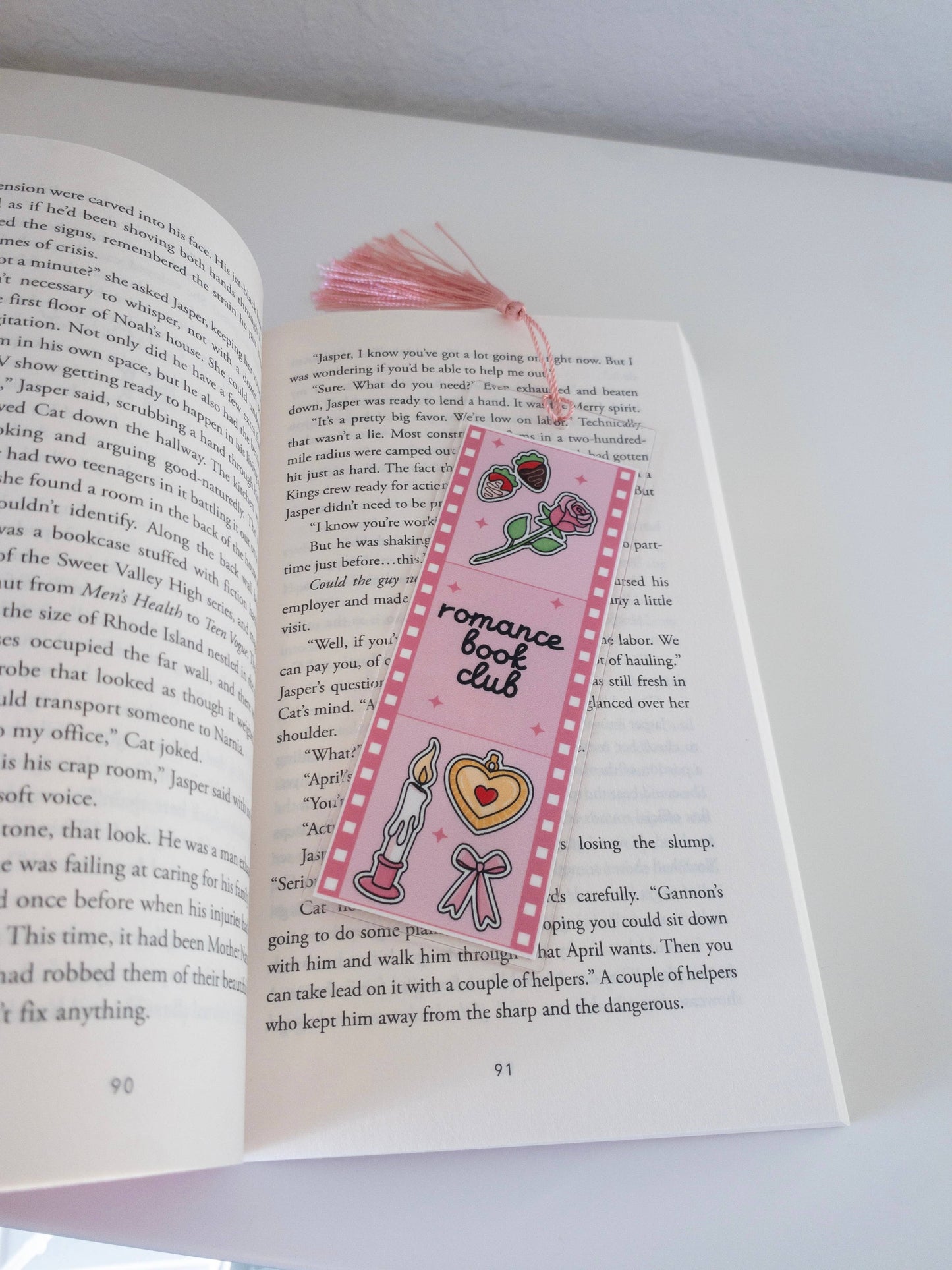 Pink bookmark with 'romance book club' design on an open book