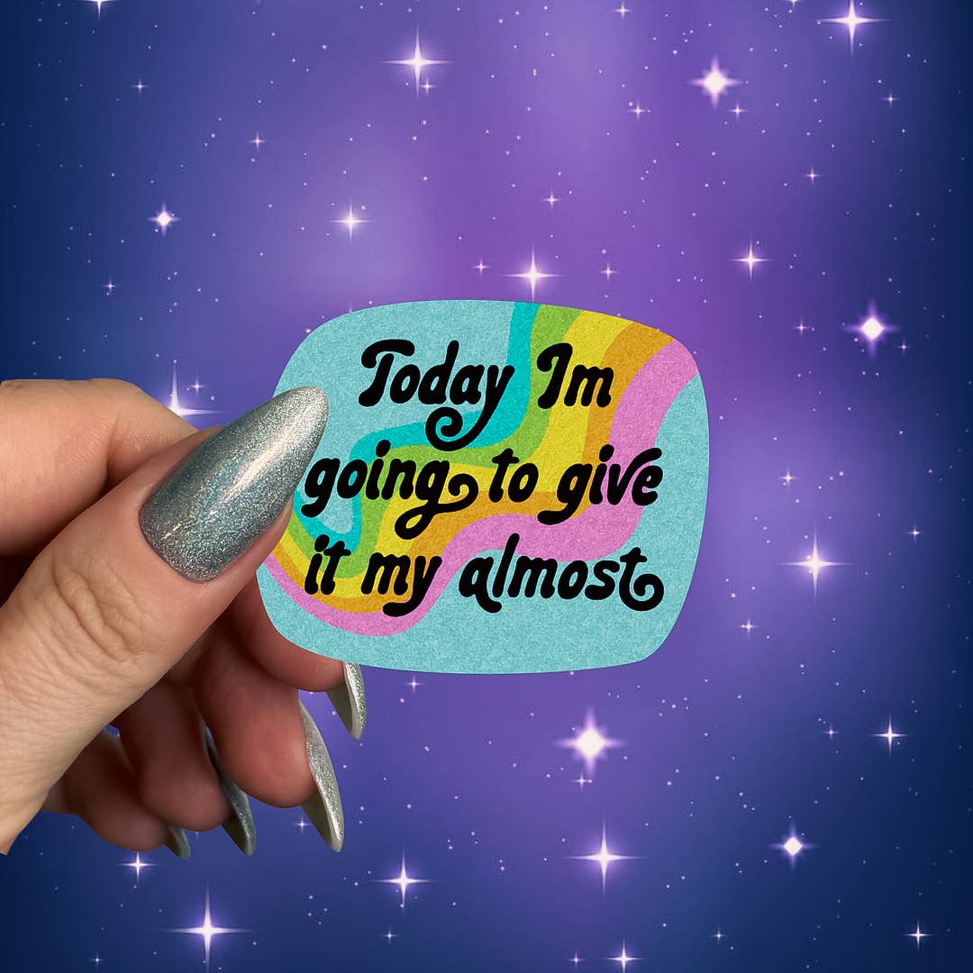 Hand holding a colorful sticker with text against a starry purple background