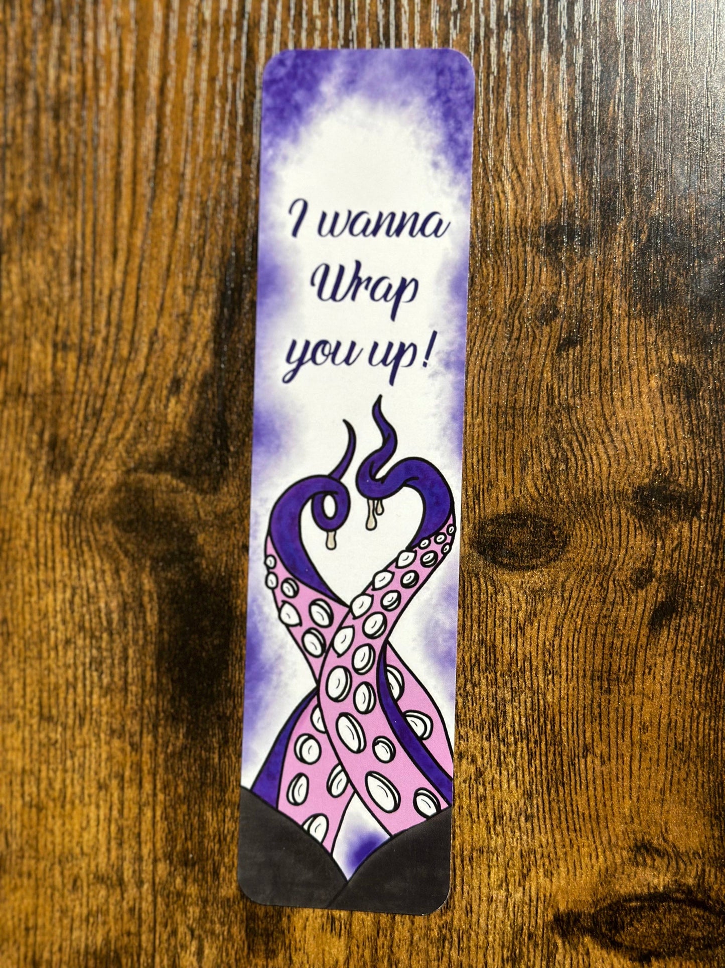 Decorative bookmark with artistic design and text on a wooden surface