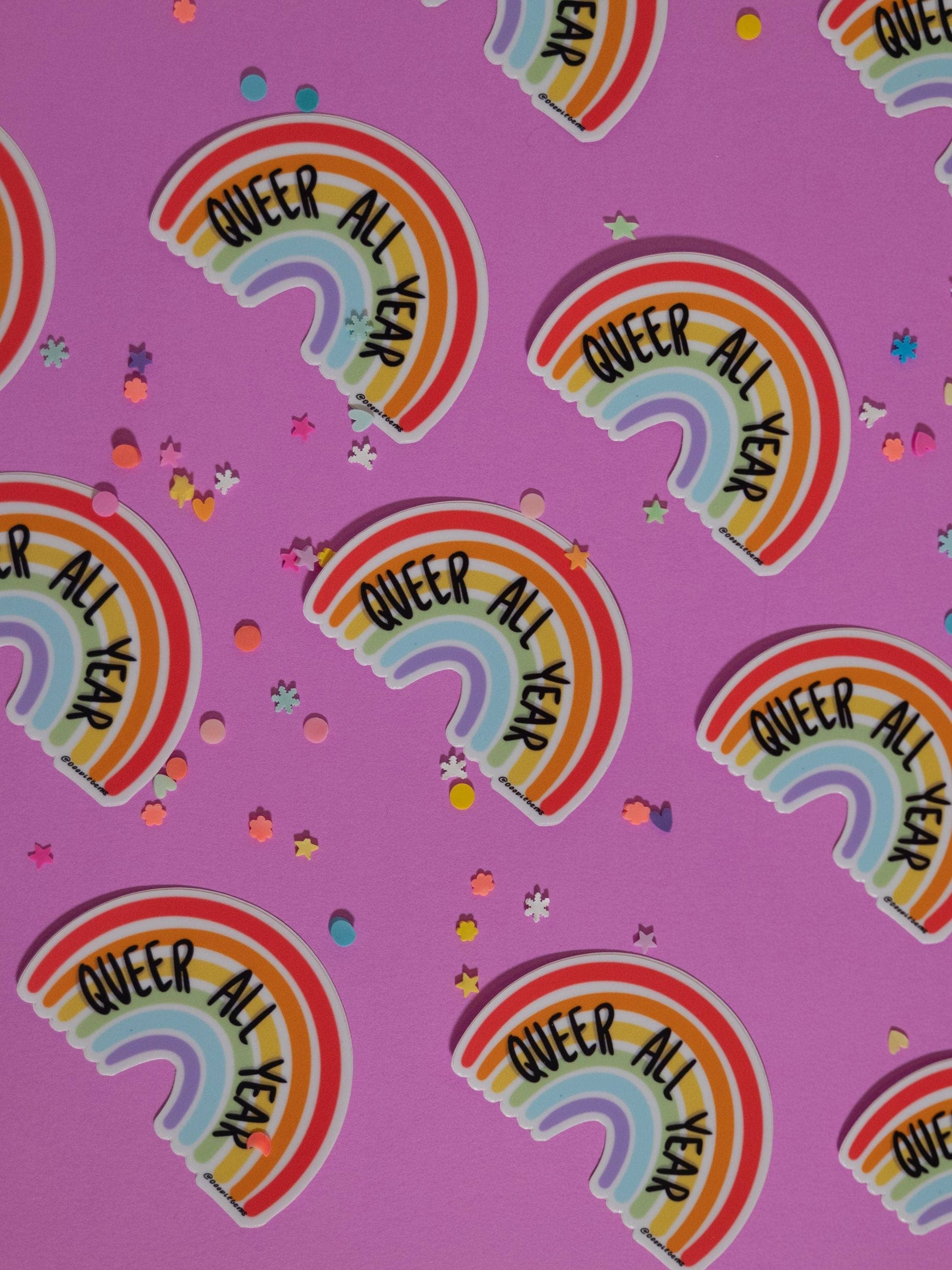 Rainbow stickers with 'Queer All Year' text on a pink background