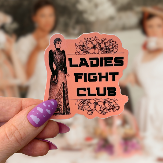 Sticker with 'Ladies Fight Club' text held by a hand with purple nail polish against a blurred background.