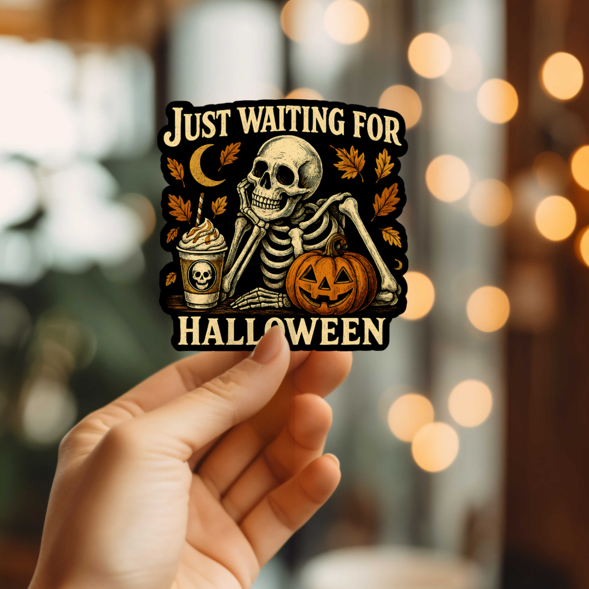 Hand holding a Halloween-themed sticker with a skeleton and pumpkin against a blurred festive background.