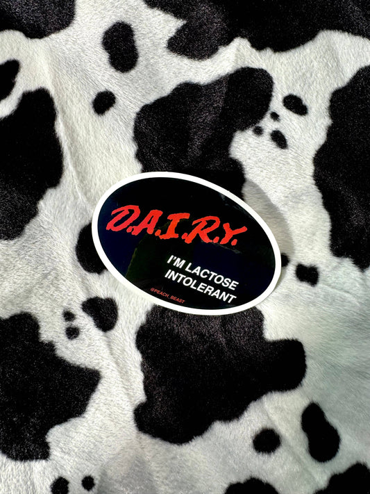 Sticker with 'DA.I.R.Y. I'M LACTOSE INTOLERANT' text on a cow print background