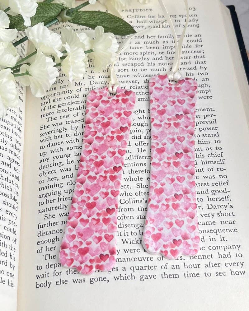 Pink heart-patterned bookmarks on an open book with white flowers.