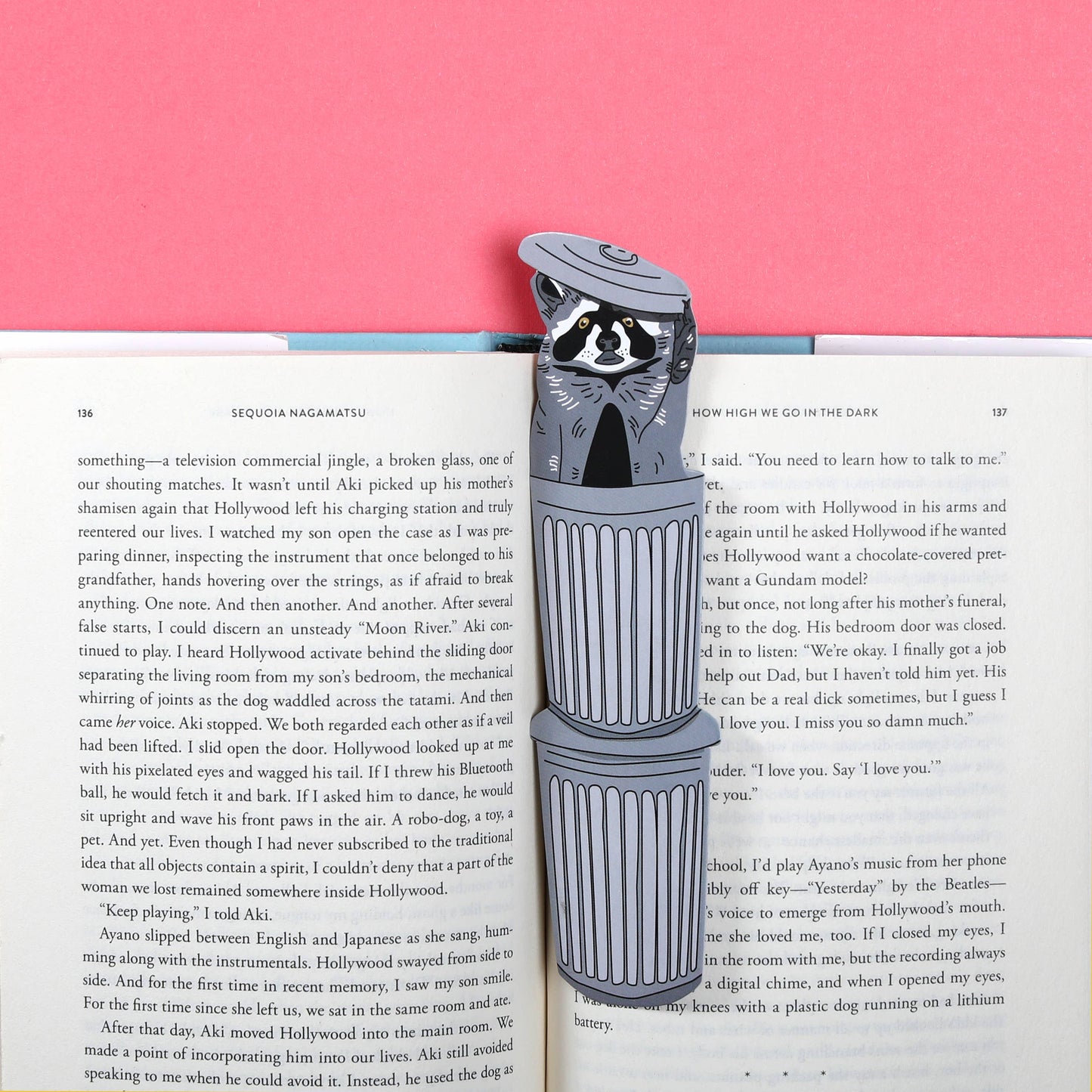Bookmark with a raccoon design on an open book against a pink background