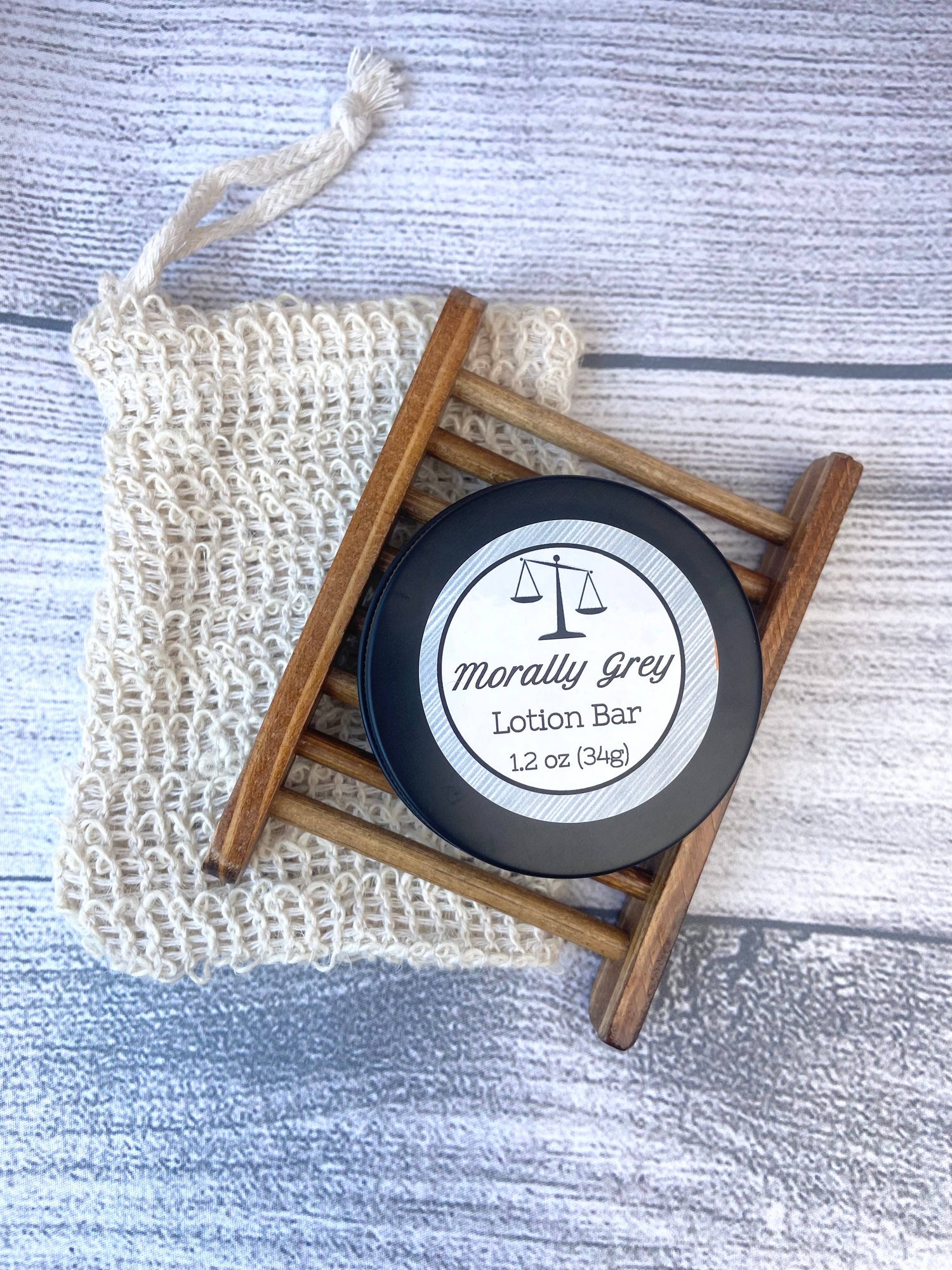 Lotion bar in a black container with 'Morally Grey' branding on a textured surface.