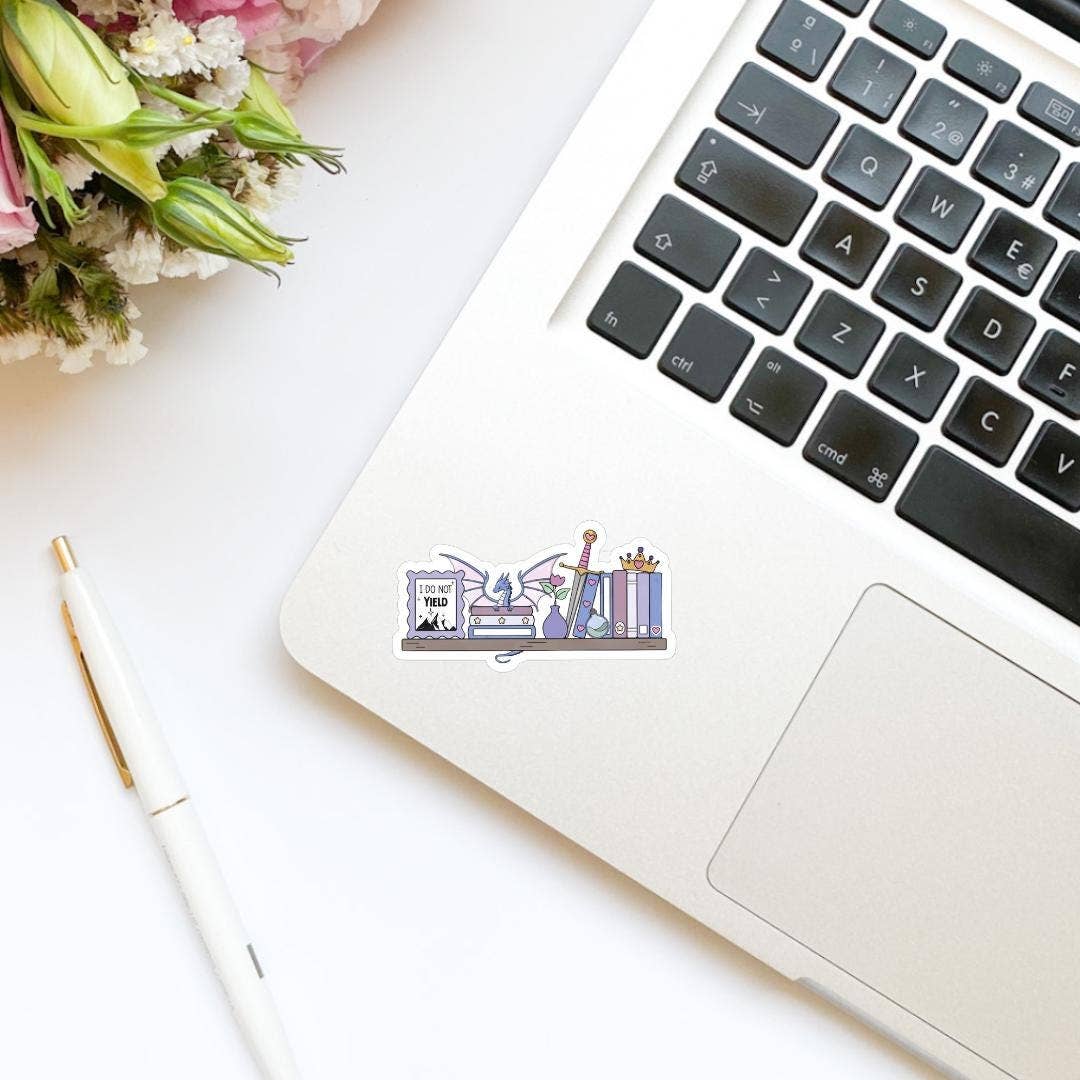 Laptop with a sticker on a desk with flowers and a pen