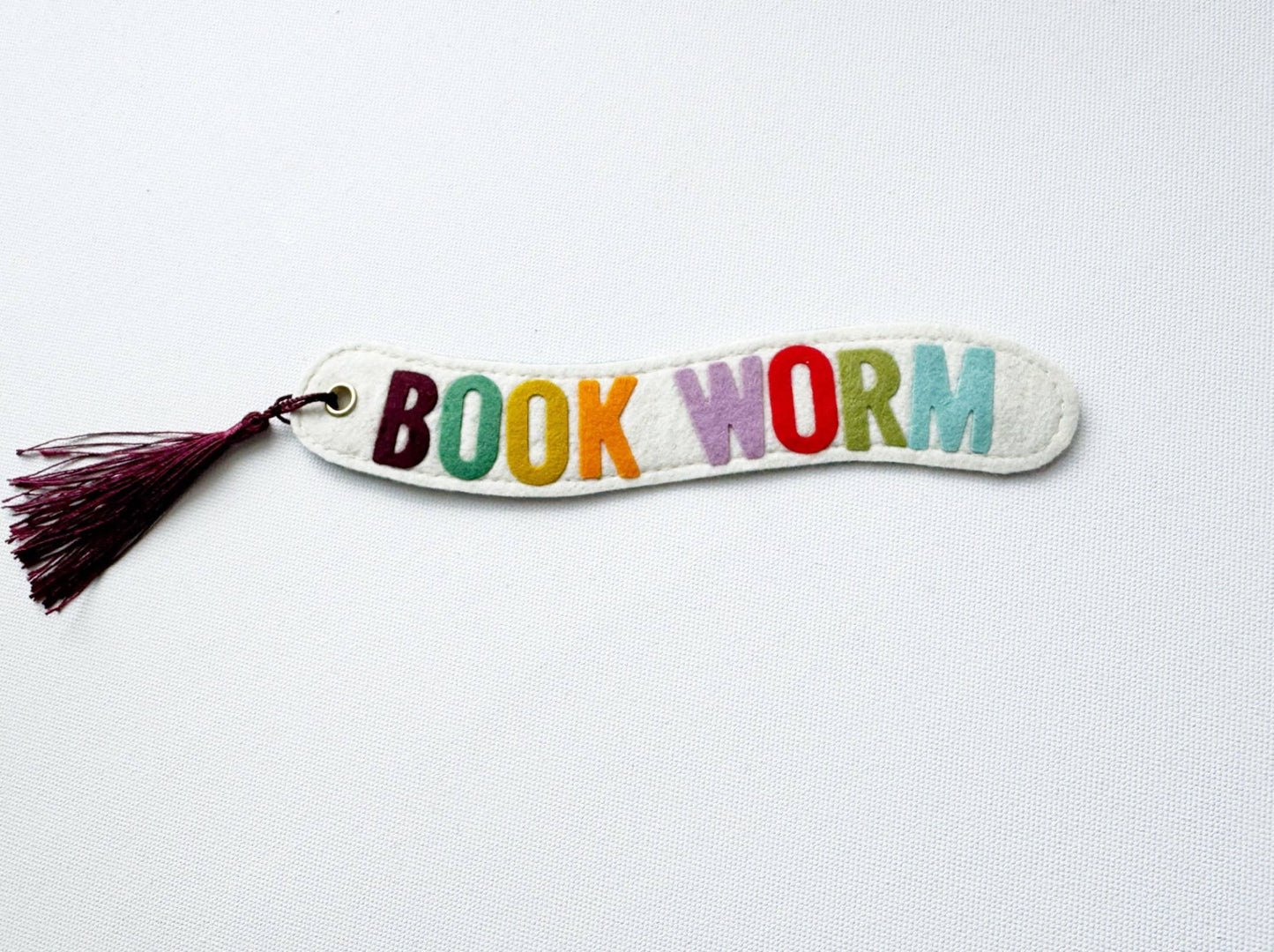 Colorful 'BOOK WORM' bookmark with a tassel on a white background