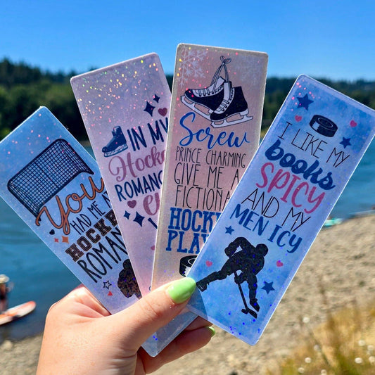 A hand holding four cardstock bookmarks with hockey-themed designs, featuring text and imagery related to the sport of hockey.