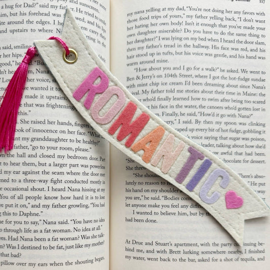 Textured bookmark with colorful letters spelling 'ROMANTIC' on a book page.