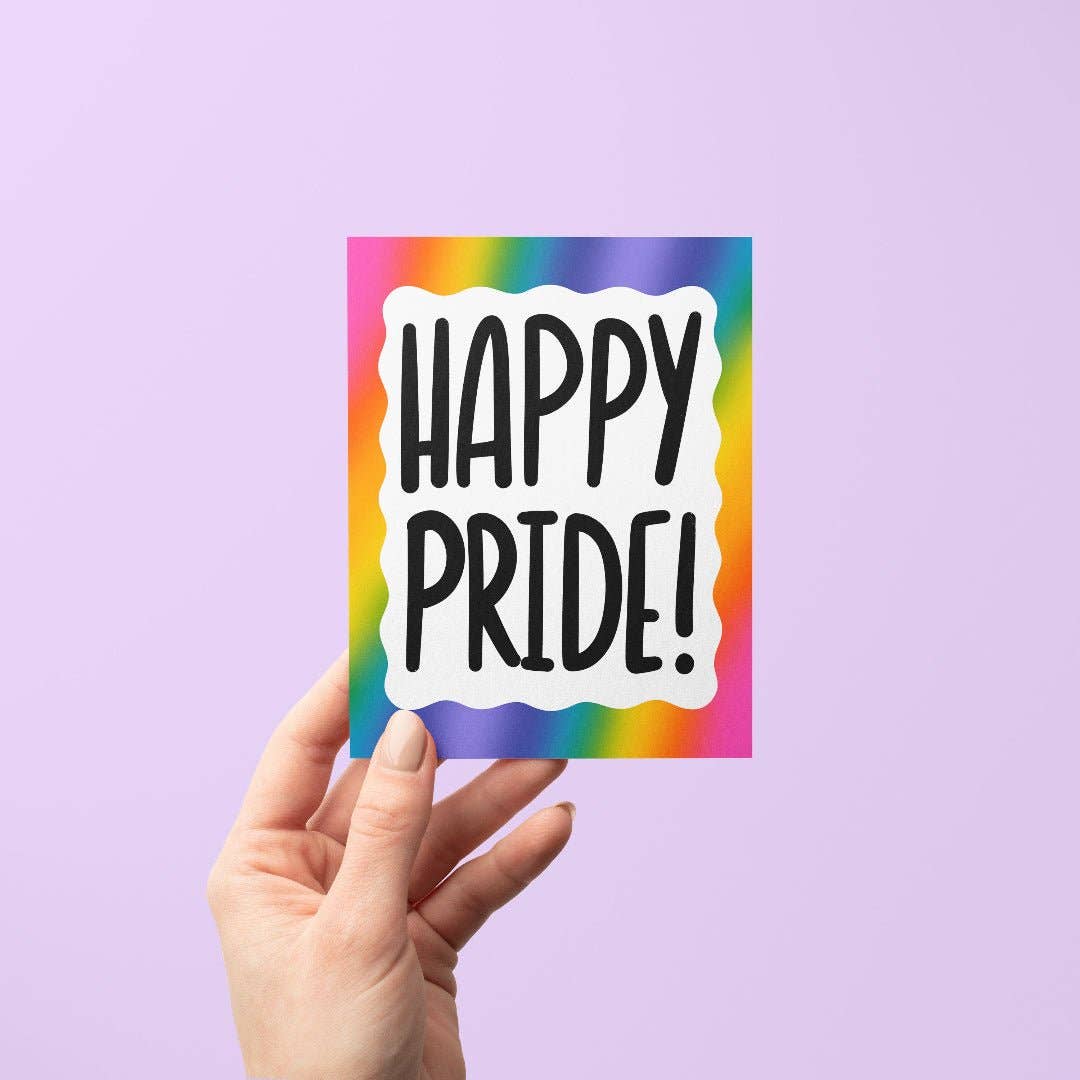 Hand holding a card with 'Happy Pride!' text on a rainbow background