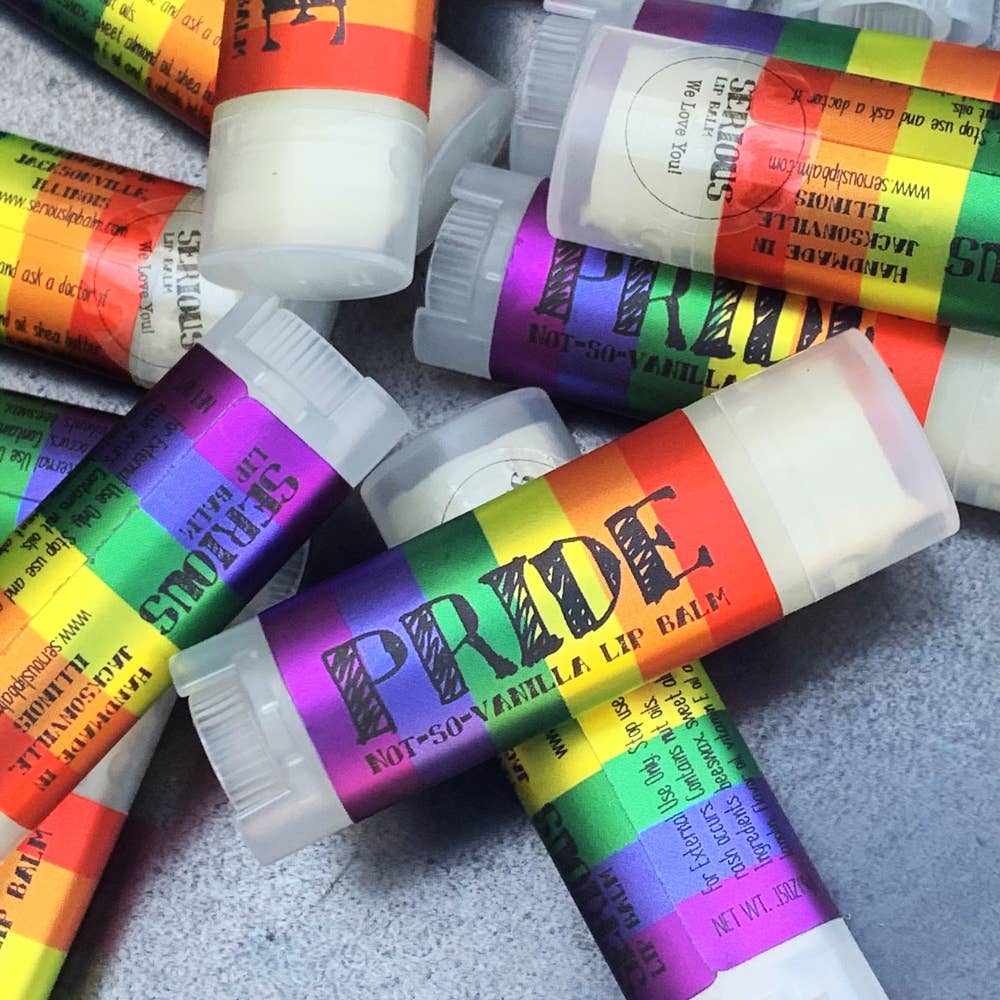 Colorful lip balm tubes with 'PRIDE' branding on a gray surface