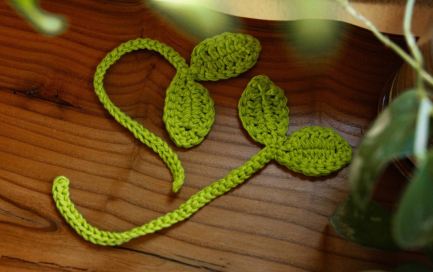 Green crocheted leaves on a wooden surface