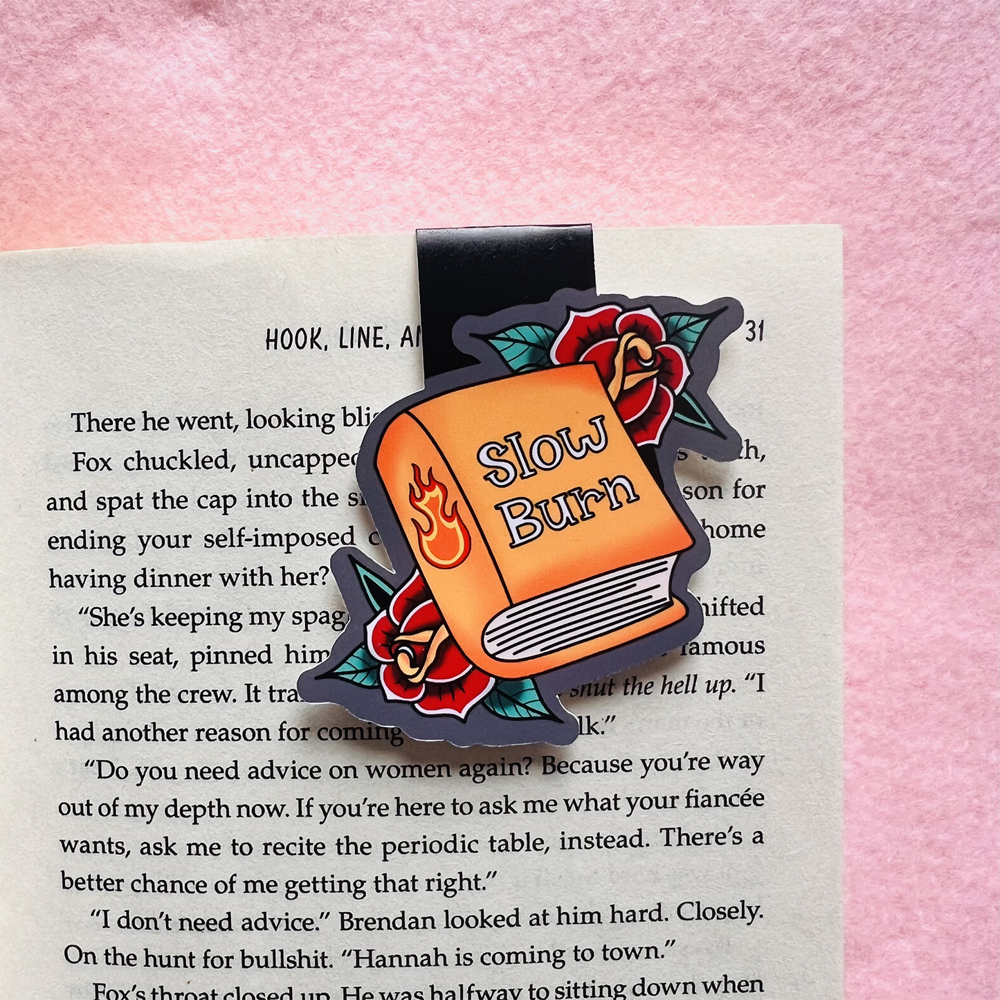 Book-shaped 'Slow Burn' enamel pin on a book page with a pink background