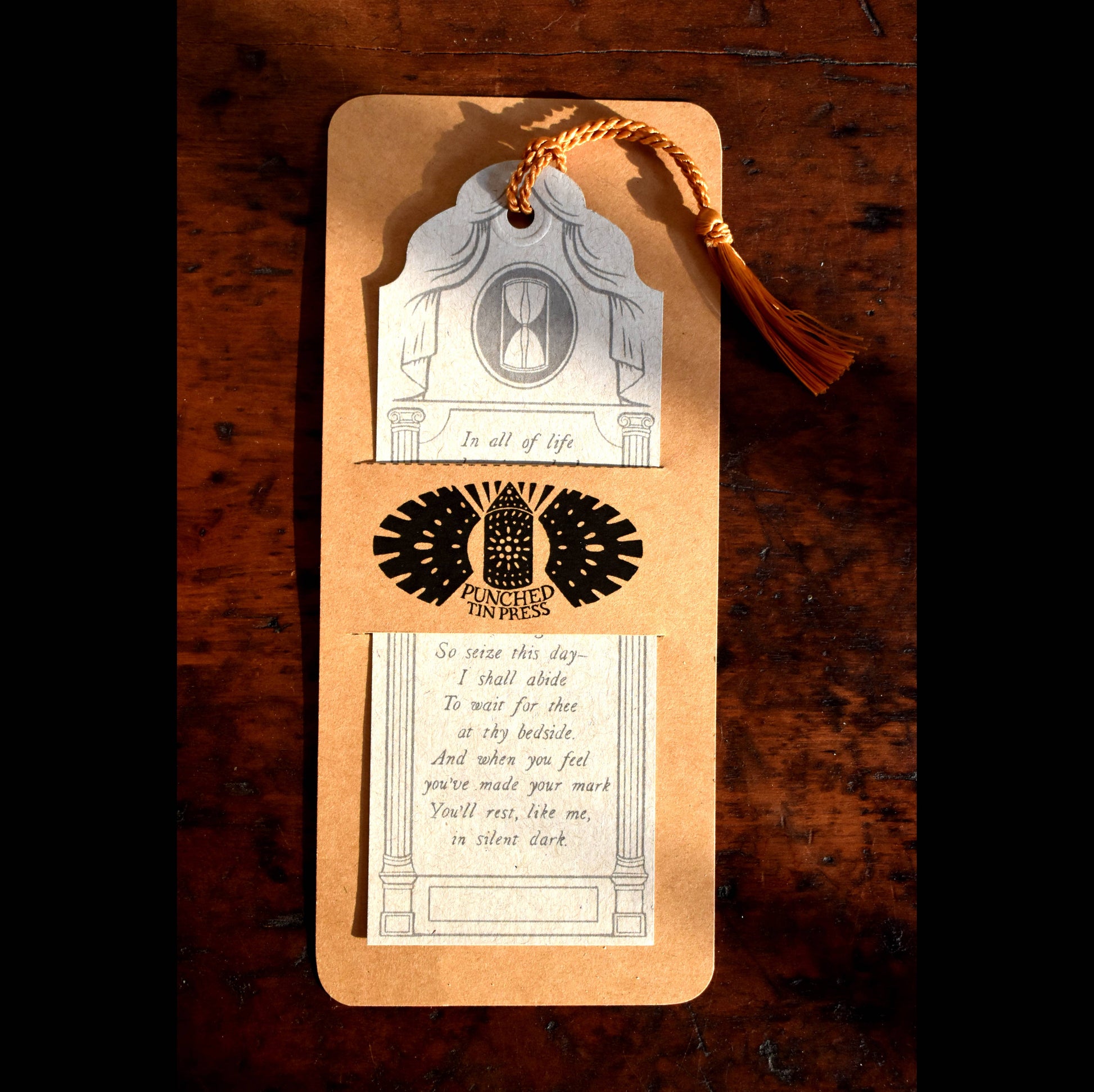 Decorative bookmark with text and design on a wooden surface