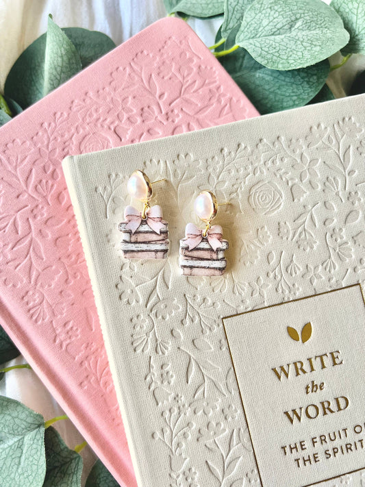 Pair of earrings on a decorative book with green leaves in the background