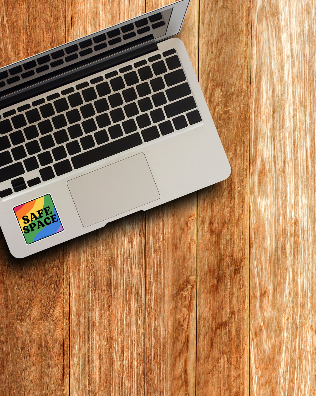 Laptop with a 'Safe Space' sticker on a wooden surface