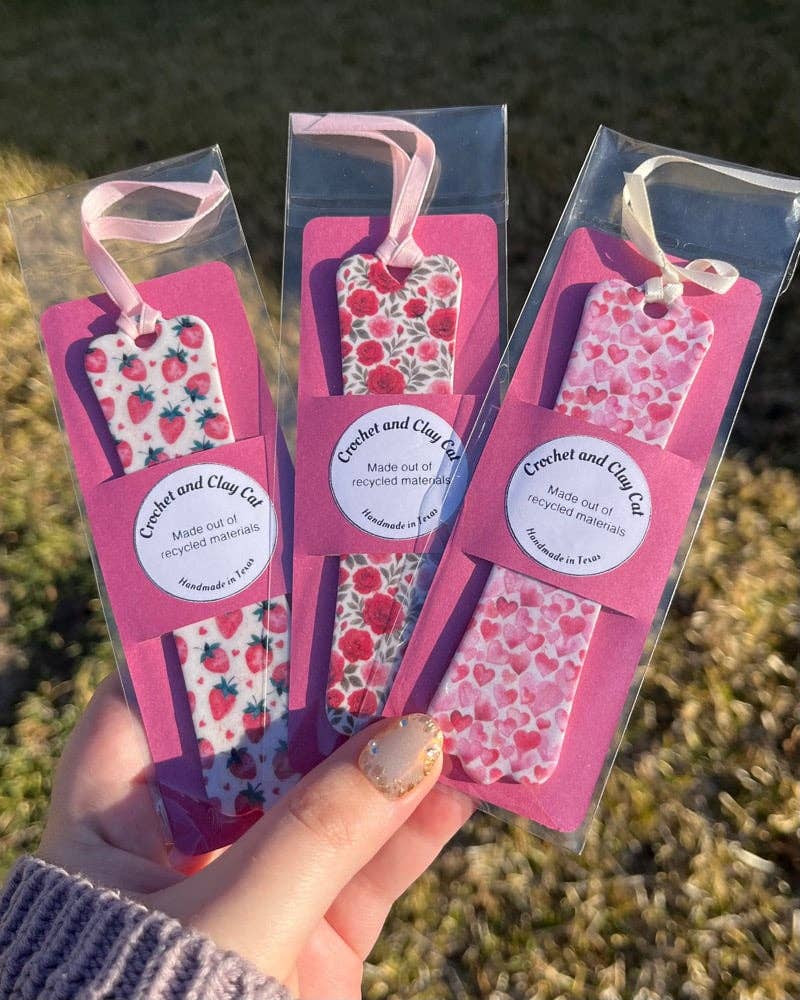 Three patterned tags in clear packaging held by a hand against a natural background