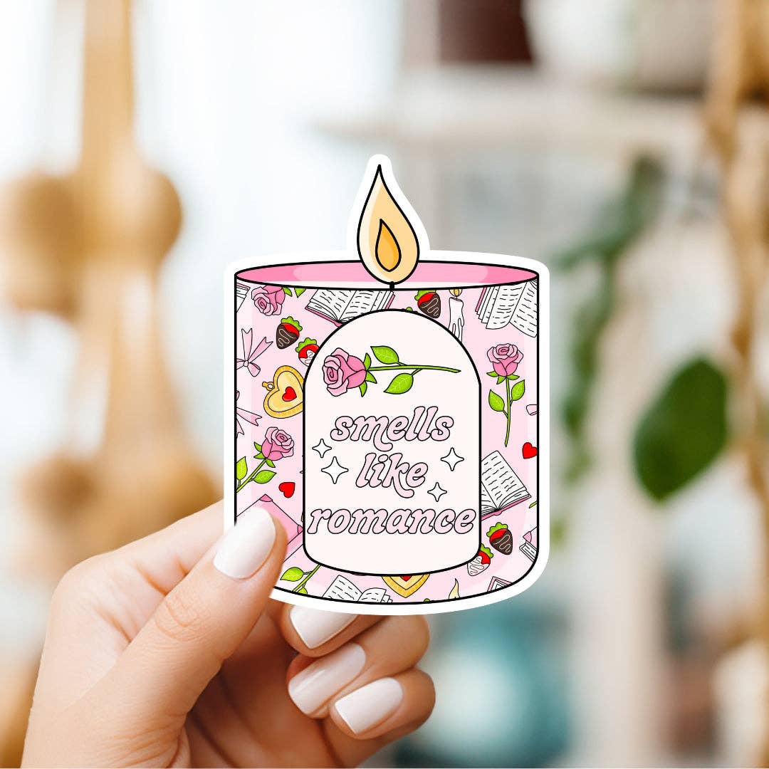Sticker of a candle with 'smells like romance' text held by a hand.