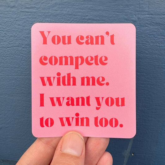 Pink card with red text held against a blue wall