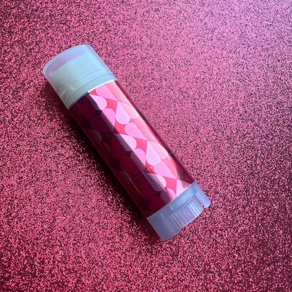 Red and gray cylindrical container with geometric pattern on a pink textured background
