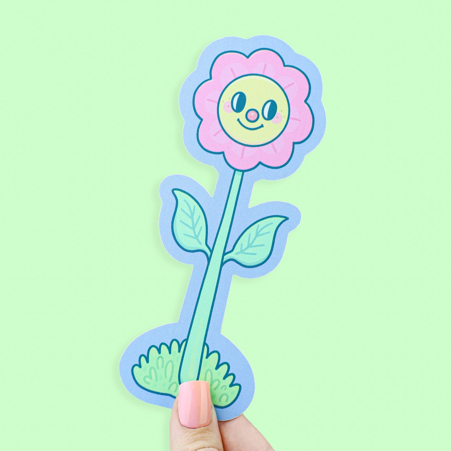 Cartoon flower sticker with a smiling face held against a light green background