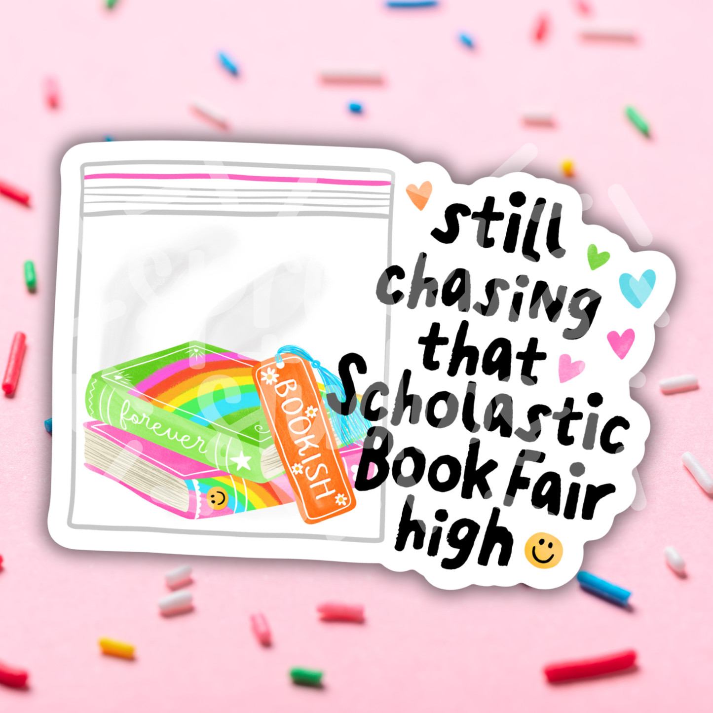Sticker with 'still chasing that Scholastic Book Fair high' text on a pink background with colorful confetti.