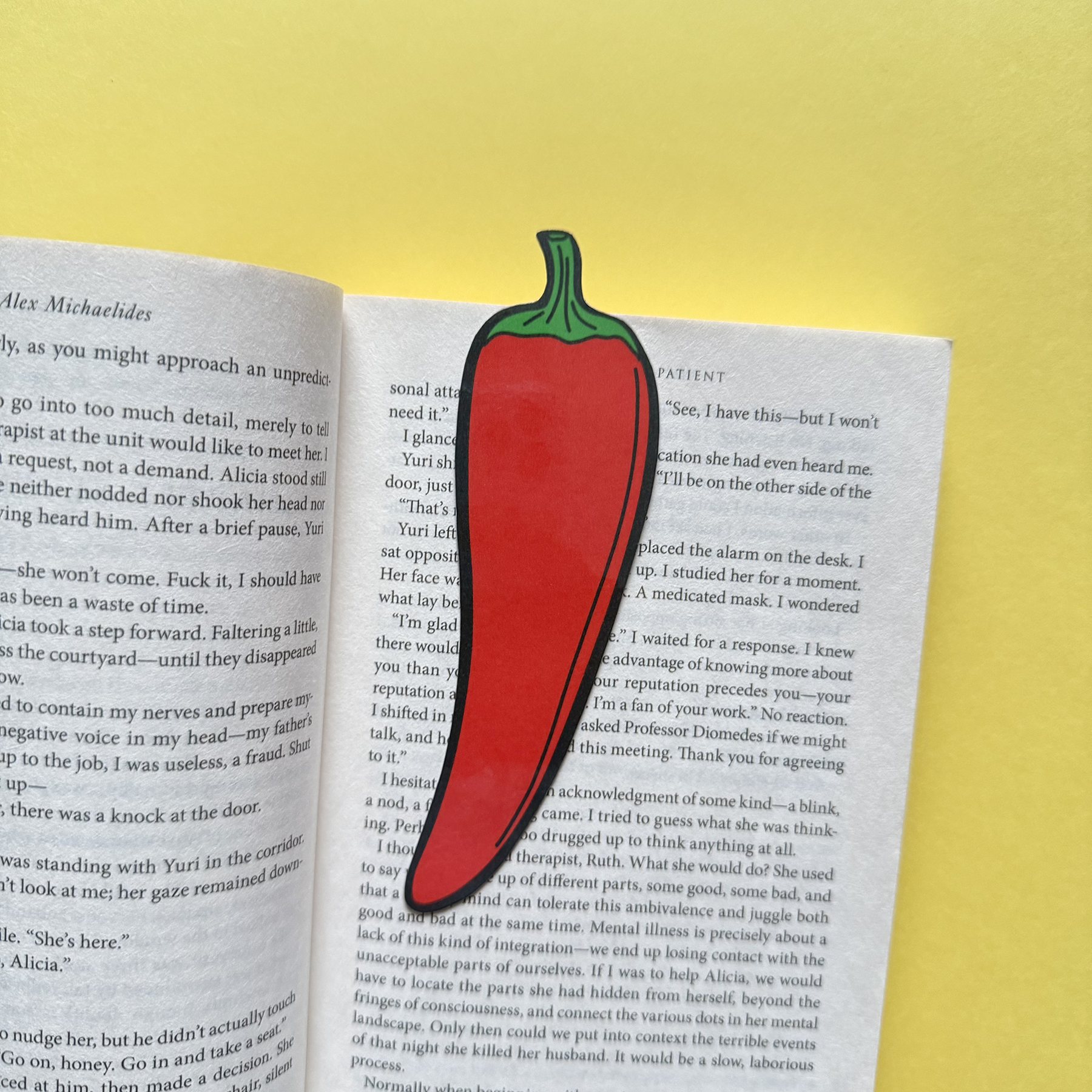 Red chili pepper-shaped bookmark on an open book with a yellow background