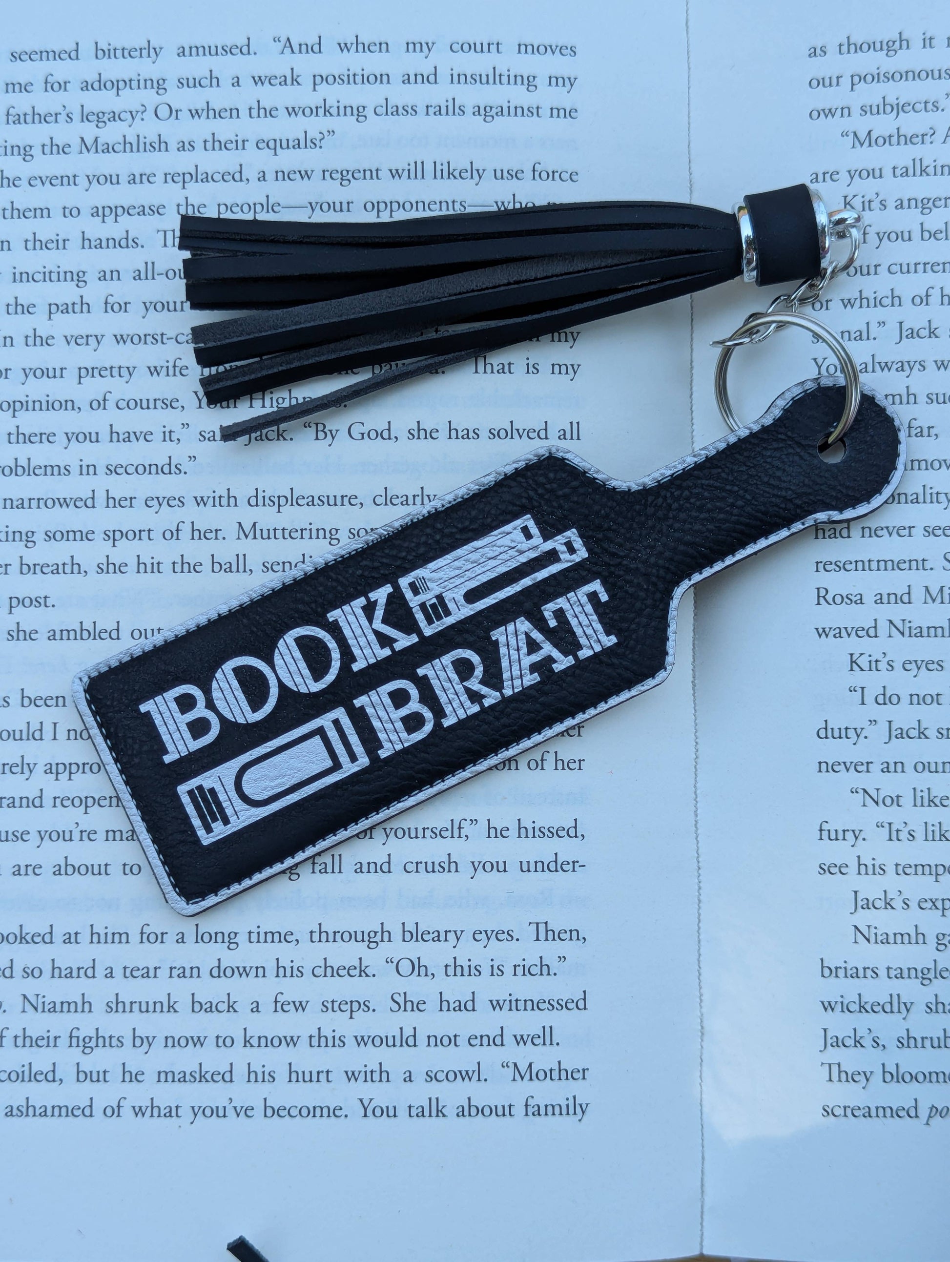 Keychain with 'Bookie Brat' text on a book page