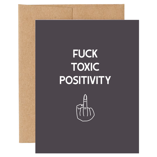 Card with 'FUCK TOXIC POSITIVITY' text and middle finger symbol on a dark background with brown envelope.