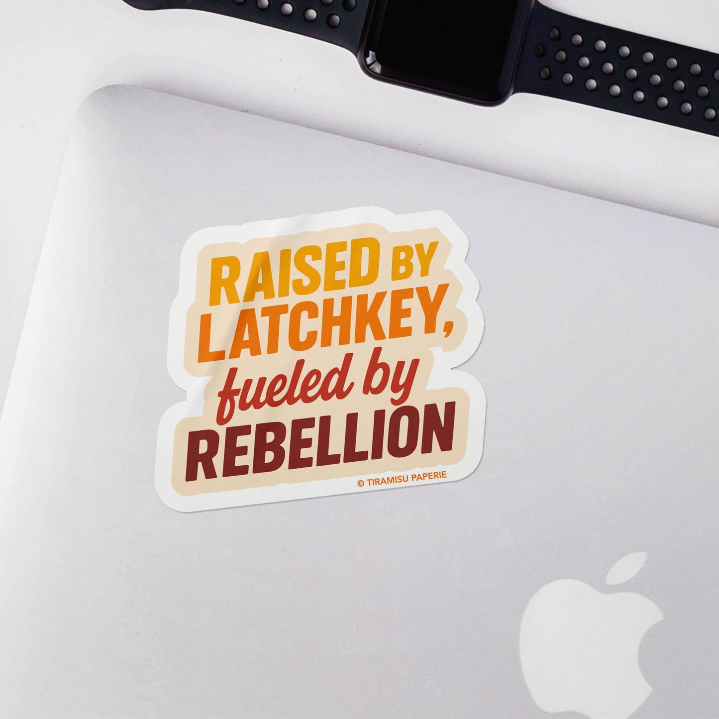 Sticker with text 'Raised by Latchkey, fueled by Rebellion' on a laptop
